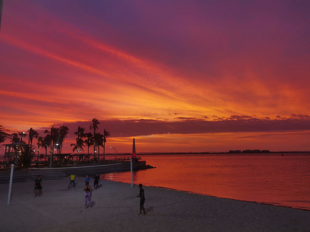 People playing beach volleyball at sunset at the malecon of La Paz