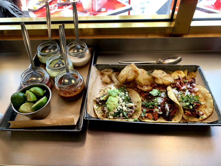 A selection of the best tacos in Mexico City on a tray with salsas next to it
