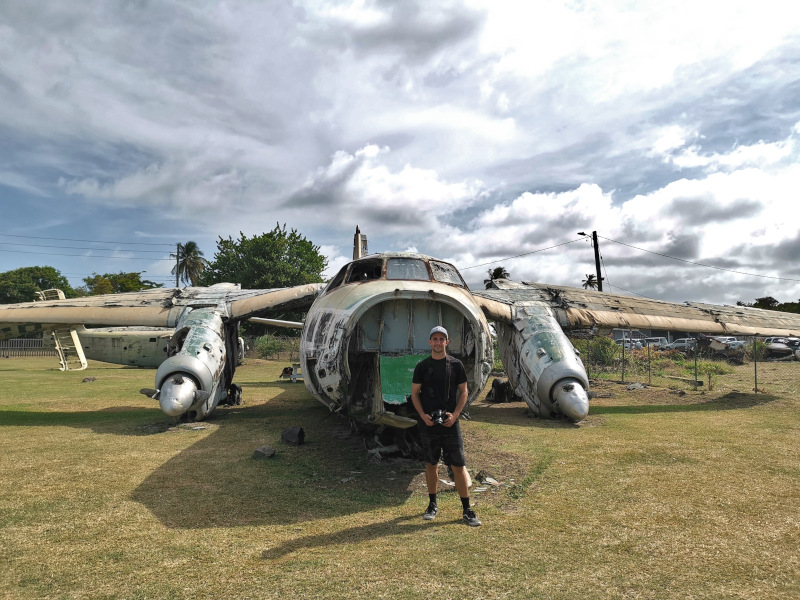 Allan holding a camera in front of an abandoned airplane
