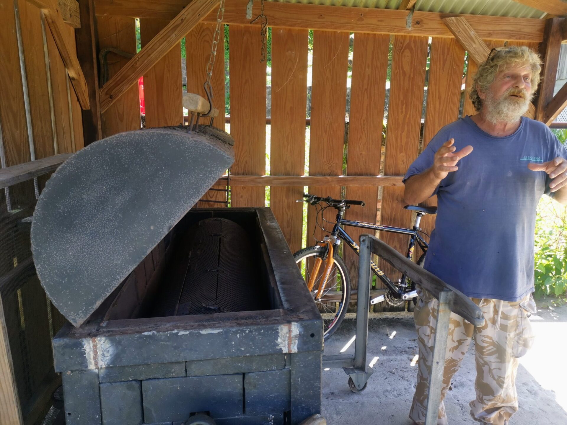 A man with a white beard and hair and blue t-shirt on giving a tour of Crayfish chocolate in Grenada, Caribbean