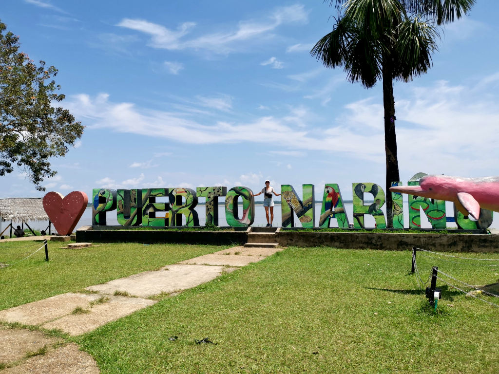 A woman standing in between the letters for Puerto Narino in the Colombian Amazon