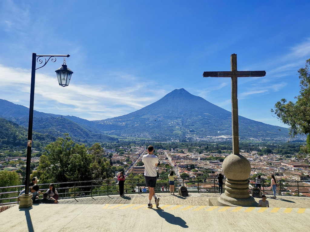 A man standing next to a cross overlooking Antigua 