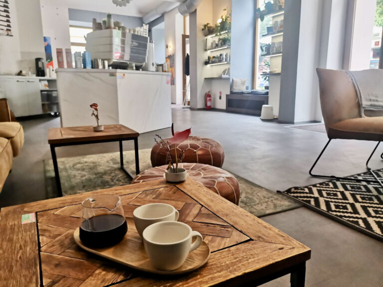 A set of two empty coffee cups and a jar with black coffee sitting on a wooden table in one of Prague's best specialty cafes