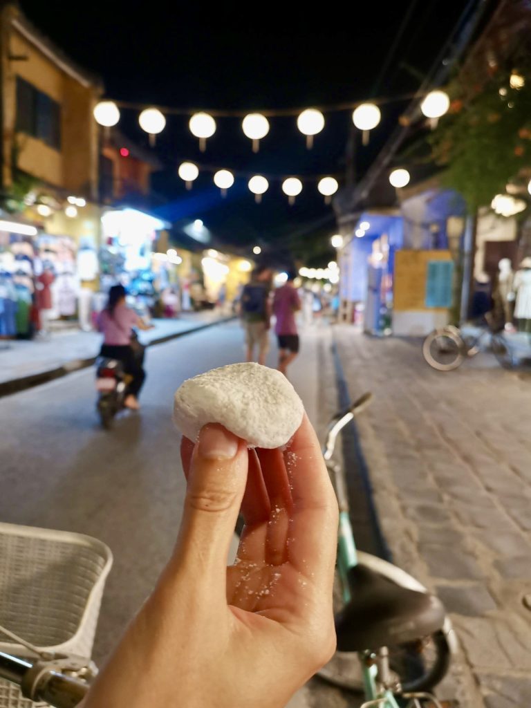 Katharina's hand holding small white glutinous mango cake a popular hoi an food