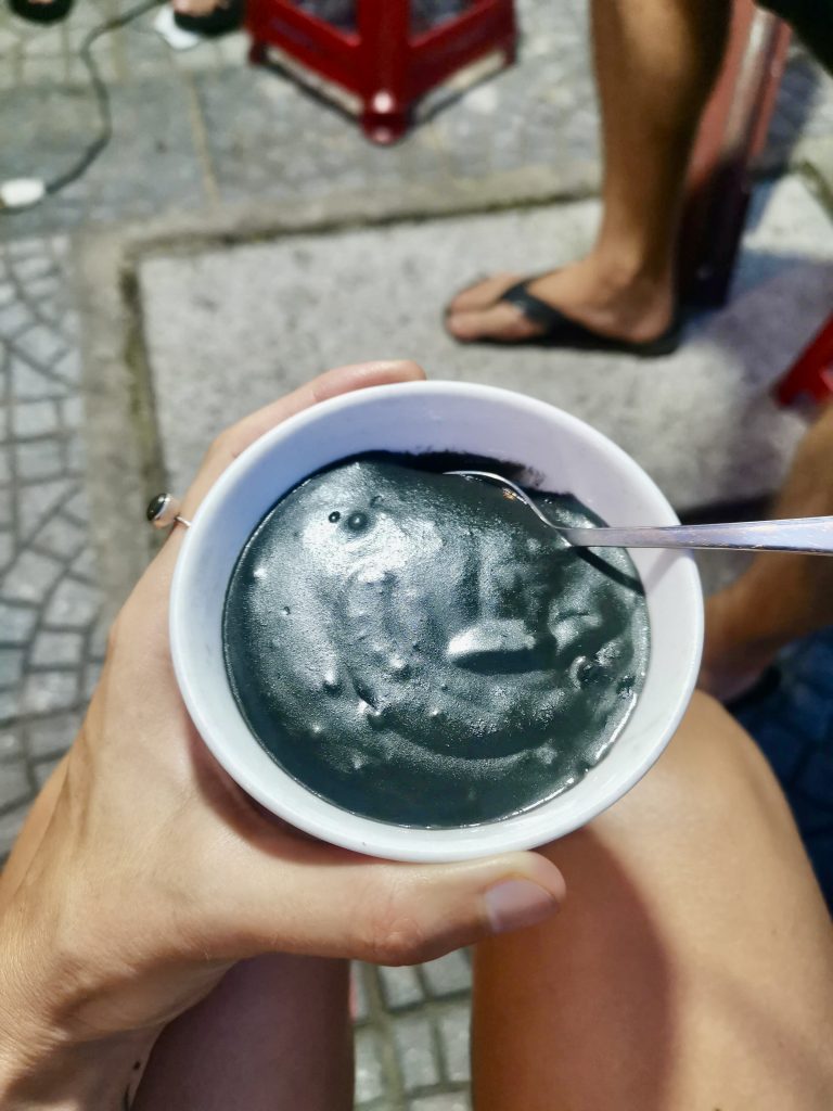 Katharinas hand holding a small bowl of Xi Ma a thick black sesame porridge made from ground sesame seeds and potato starch.