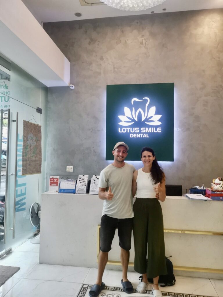 A foreign digital nomad smiling while sitting in a modern, high-quality dental chair in Da Nang, illustrating the cost-saving benefits of dental tourism in Vietnam.