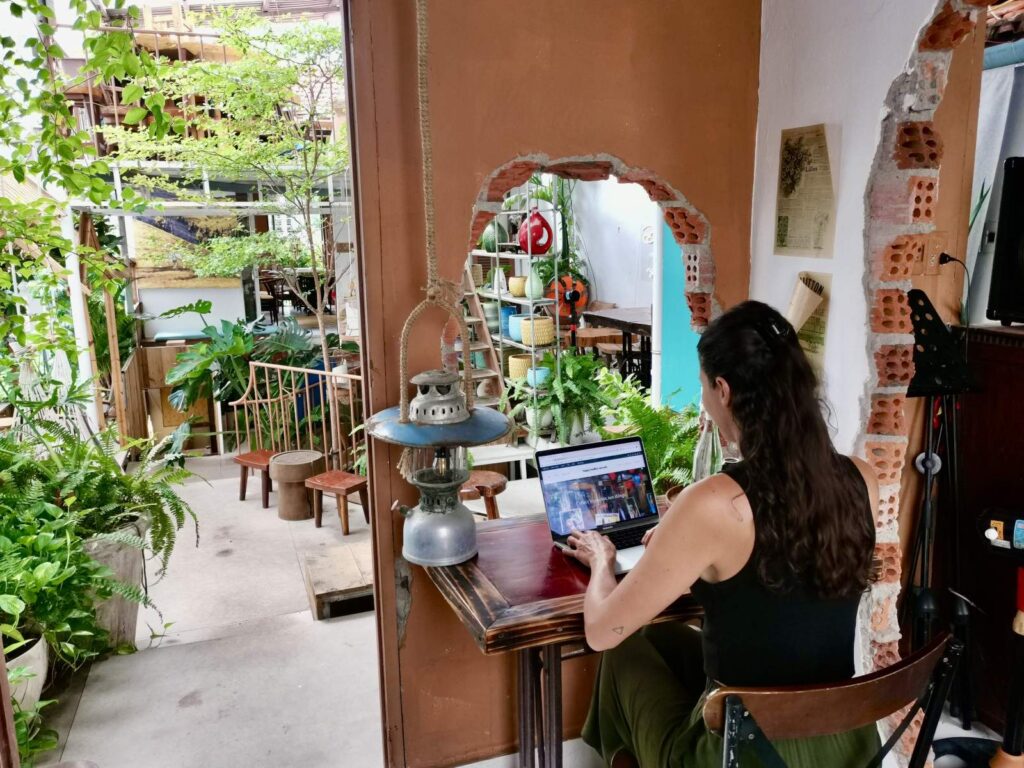 Katharina working on a laptop at a wooden table inside Phin Cu Cafe in Da Nang, illustrating the city's excellent work-friendly cafe scene for digital nomads.