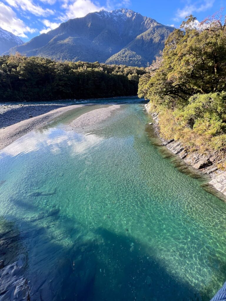 Crystal clear turquoise water of the Blue Pools surrounded by lush forest and mountains in Haast Pass.