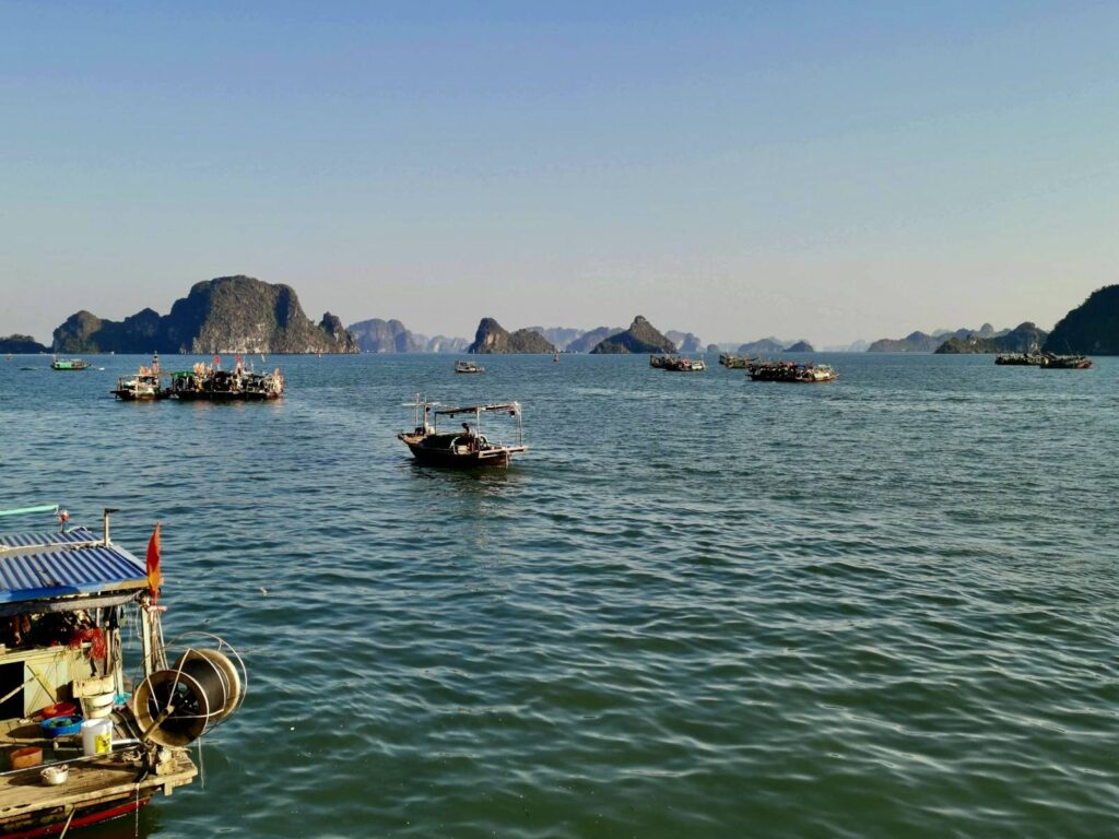 Traditional fishing boats floating in Ha Long Bay surrounded by limestone islands in Vietnam