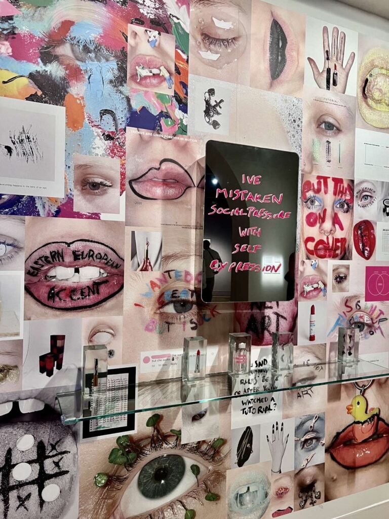Contemporary art wall collage featuring lipstick tubes in clear resin blocks and a mirror reading "I've mistaken social pressure with self expression" at CCCB in Barcelona.