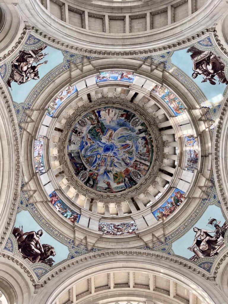 Looking directly up at the intricate painted frescoes and architectural details inside the central dome of the MNAC museum in Barcelona.
