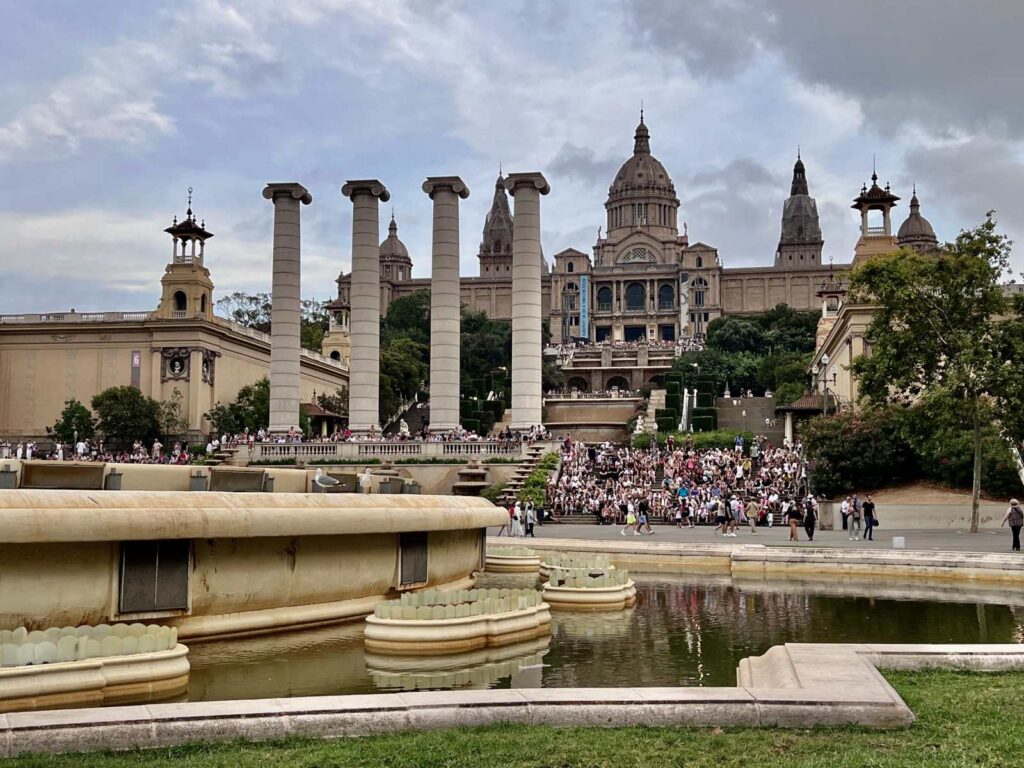Wide exterior view of the Four Columns and the majestic Palau Nacional building housing the MNAC museum on Montjuïc hill in Barcelona.