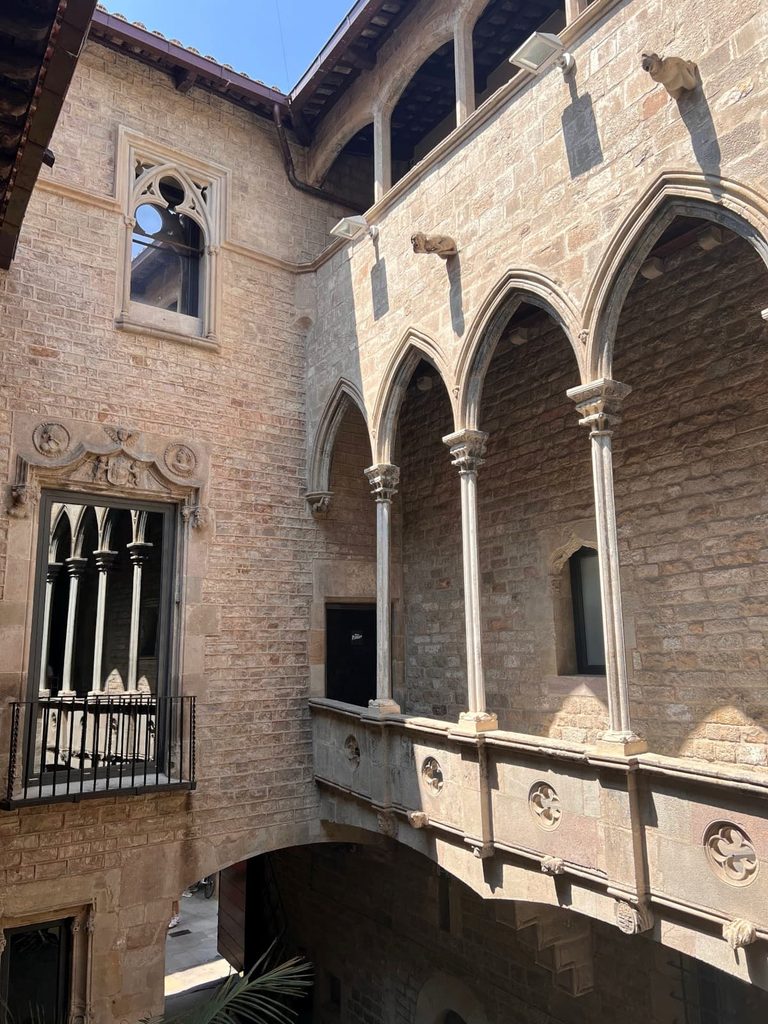 Gothic-style stone arches, gargoyles, and an upper gallery inside the central courtyard of the Picasso Museum in Barcelona.
